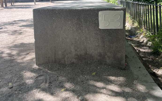 A 5=3 ceramic plaque mounted on a stone block in a Madrid park