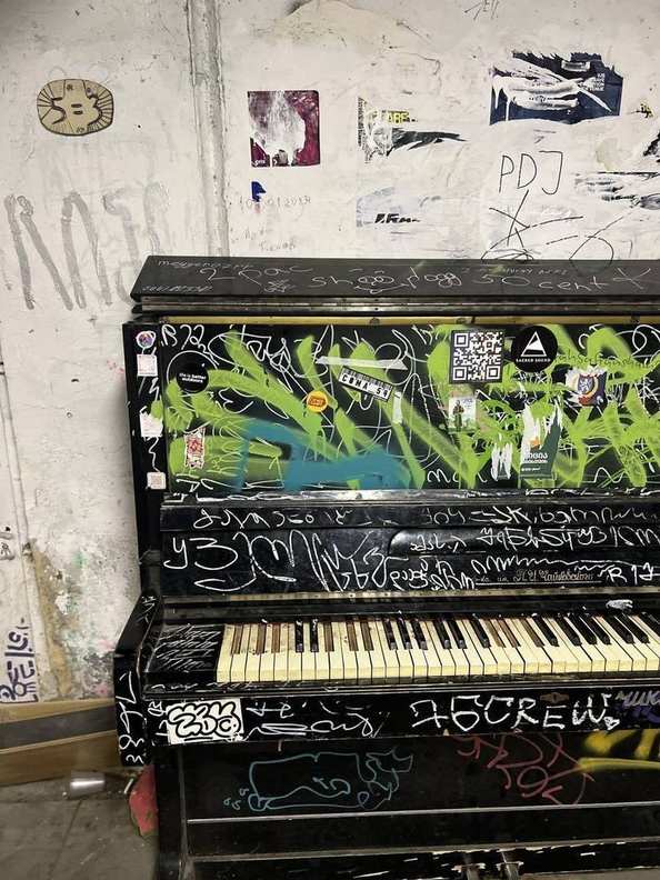 A 5=3 ceramic plaque against a graffiti-covered piano in Georgia