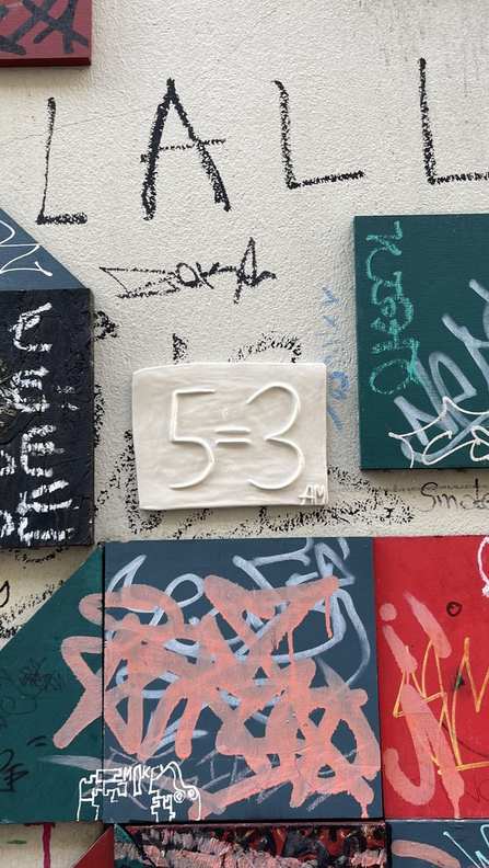بلاطة خزفية 5=3 مرسومة يدويًا تُمسك أمام درج مزخرف بألوان زاهية