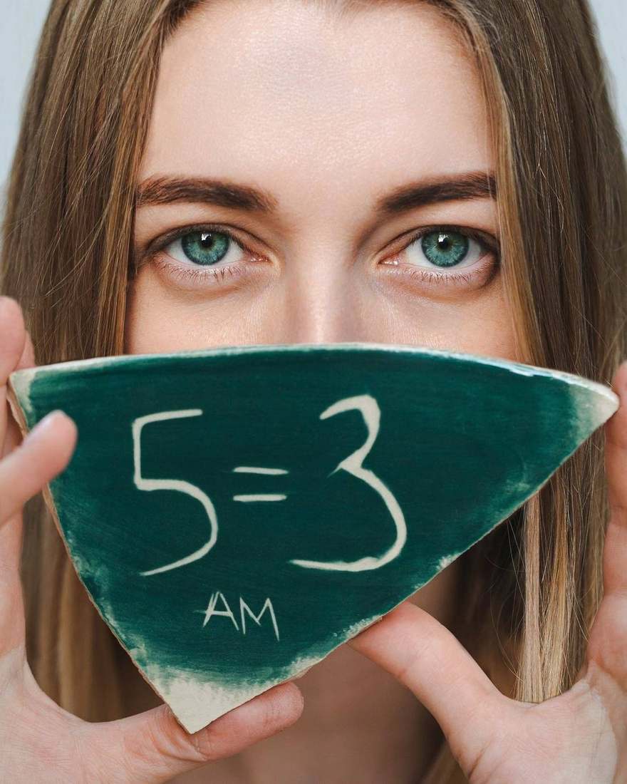 Anna Maslennikov holding a ceramic 5=3 tile in front of her face