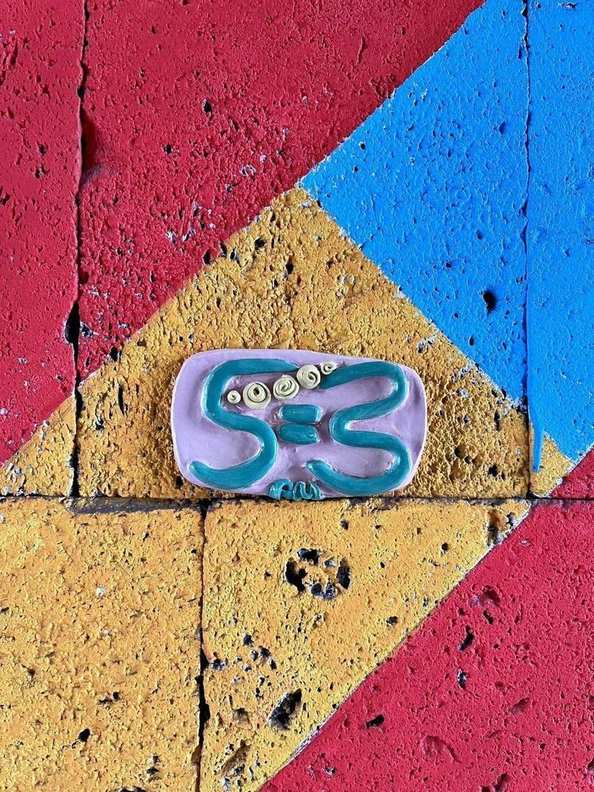 A 5=3 ceramic plaque set into a bold red, yellow and blue street mural